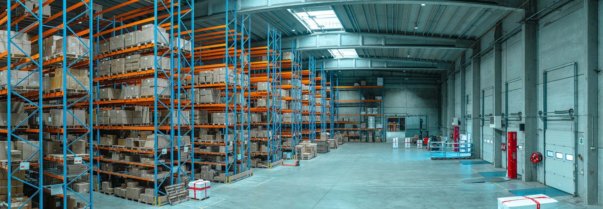 Tall blue metal shelving units filled with cardboard boxes in a large warehouse